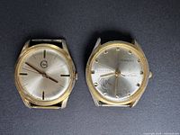 Front view of two vintage Swiss wristwatch heads, showing dials and cases