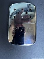 Front view of polished chrome Zippo hand warmer showing vent holes and logo