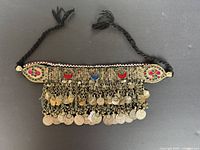 Full view of necklace showing braided ties, metal panel, coin fringe