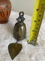 Full view of brass bell beside tape for scale