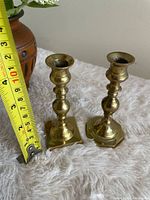 Pair of brass mini candlesticks beside ruler showing 4.25 in height