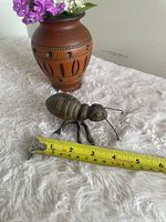 Overall view showing cast iron ant next to tape measure for scale