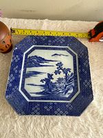 Full view of octagonal flow blue plate with tape measure indicating size