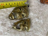 Both brass masks with tape measure showing length