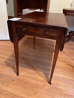 Full view of table with one leaf down showing drawer front and tapered legs