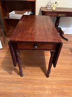 Table front view with leaves down, showing drawer and turned legs