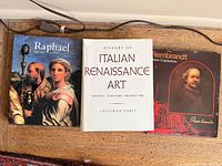 Three art books side by side on floor: Raphael, History of Italian Renaissance Art, Rembrandt