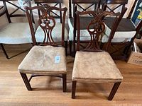 Front view of both carved wood chairs with leather seats