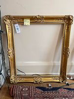Full view of gold ornamental frame leaning against wall