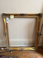 Full view of ornate gold frame leaning against wall