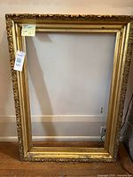 Full view of gold ornate picture frame leaning against wall