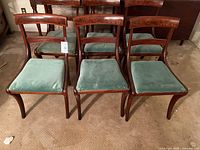 Front view of six mahogany chairs with green velvet seats
