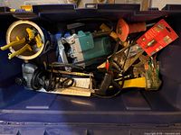 Blue Makita router, black corded sander, tin snips and other tools inside blue tote