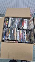 Open box showing rows of DVD cases, some titles readable