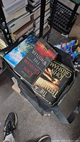 Bag containing visible John Grisham paperbacks The Guardians, The Whistler, The Testament and Sycamore Row