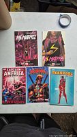 All five trade paperbacks laid out: two Ms. Marvel, one Captain America, two Deadpool