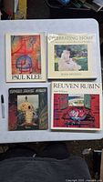 All four books laid out: Paul Klee, Celebrating Home, Brawer Bunte Mauer, Reuven Rubin