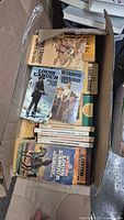 Open box showing top layer of Louis L’Amour paperbacks with visible titles and cover art