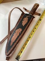 Knife in sheath next to tape measure showing length