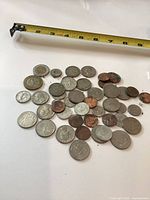 Overall pile of mixed coins with tape measure for scale
