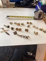 Overall layout of cufflinks, tie bars and tie tack with tape measure for scale