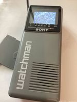 Front view showing screen with static, antenna, speaker grille and watchman branding