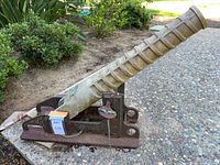 Left side view of brass line throwing tool on iron carriage outdoors