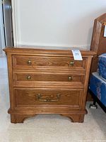 Front view of oak nightstand showing drawers and brass hardware