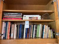 Two shelves filled with assorted cookbooks, visible spine titles and spiral-bound volumes
