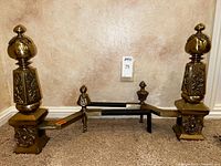 Full view of both brass andirons joined by billet bars