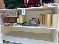 Shelf with hurricane shade, boxed shade, assorted candles, box labelled shells