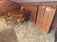 Dining table with four chairs and three leaves leaned against wall