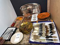 Overview of flatware set, trays, enamel plates, fondue forks, Heath dish