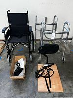 Wheelchair, two walkers, footrests in box, wood board and straps on floor