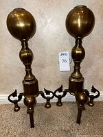 Full view of both brass andirons standing upright
