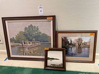 Front view showing three framed artworks: large barge painting, medium photograph, small geese painting