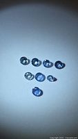 Eight round blue gemstones arranged on white background