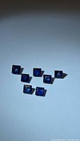 Seven square blue sapphires on neutral background