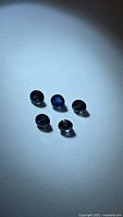 Five round deep blue sapphires on light background