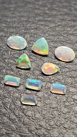 Eight mixed-cut Ethiopian opals on black textured background