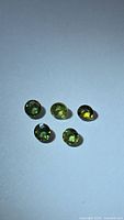 Five round yellow-green sapphires on neutral background