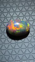 Top view of oval Ethiopian black opal showing multicolour play-of-colour