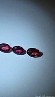 Three oval cut deep red-pink sapphires side by side