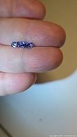 Three cushion-cut blue tanzanites on fingertip