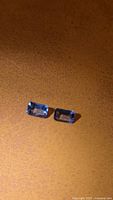 Pair of rectangular blue tanzanites on brown background