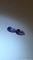 Both pear-cut tanzanites on neutral background