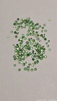 Loose green tsavorite garnet stones spread on surface