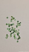 Group of small green round gemstones spread on surface