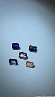 Five emerald-cut sapphires displayed on white background showing color range
