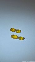 Four yellow oval sapphires on white background